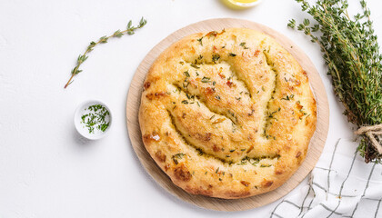 Fresh focaccia with herbs on white table. Classic Italian bread. Tasty food. Baked goods. Top view.