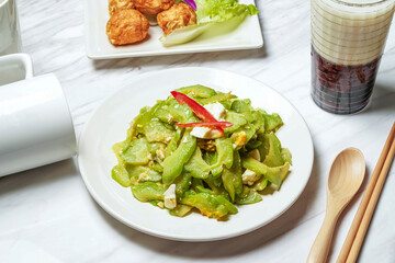 Fried Bitter Melon with Salted Egg with Fried squid balls, Taiwanese red bean ice tea served in dish isolated on marble background side view of taiwan food
