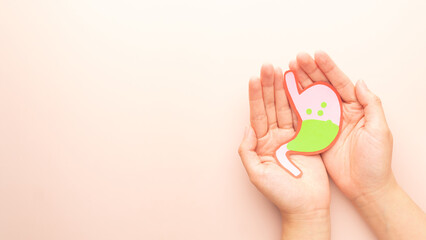 Human hands holding stomach with gastric acid made from paper. Gastroesophageal reflux disease (GERD) or acid reflux symptoms. Gastrointestinal system disease and digestive problems.