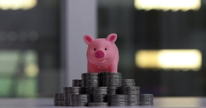 Pink piggy bank for reduction on a stack of coins