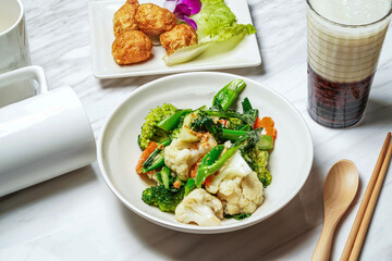 Garlic mixed vegetables with cauliflower, broccoli, kailan, Fried squid balls,Taiwanese red bean ice tea served in dish isolated on marble background side view of taiwan food