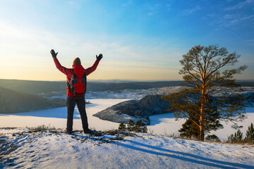 Happy man hiker with raised arms in snow covered winter nature. Freedom, people at nature.