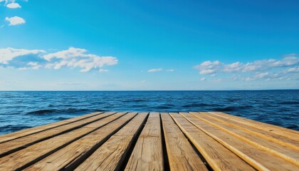 Fototapeta premium A serene wooden pier extending over calm waters under a clear blue sky, perfect for relaxation and nature photography.