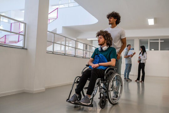 Group of diverse college students in university hallway, a classmate pushing a friend in a wheelchair as they walk down the school corridor or caregiver walks with a patient through hospital corridor. - Powered by Adobe