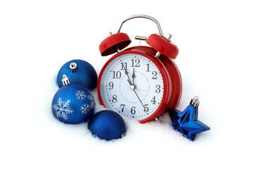 An alarm clock with Christmas tree decorations lies on the snow with space for text.