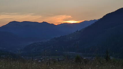Fototapeta premium sunset in the mountains, beautiful view of mountains and houses at sunset