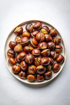 Casta&ntilde;as asadas servidas en un plato blanco sobre un fondo claro. Un aperitivo cl&aacute;sico y sabroso, ideal para disfrutar en los meses de oto&ntilde;o.