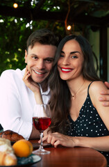 Happy Valentine's day, anniversary, and birthday. Couple sharing a joyful moment while enjoying pastries and drinking red wine in a cozy outdoor café. Man and woman sitting closely in restaurant