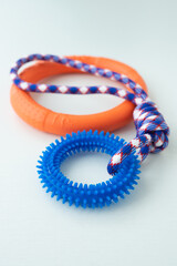 Orange puppy pull ring and blue knot tugger. Best dog toys for training and education, and scratching teeth on white background.