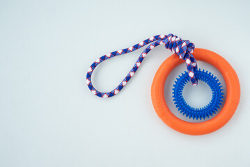 Orange puppy pull ring and blue knot tugger. Best dog toys for training and education, and scratching teeth on white background.