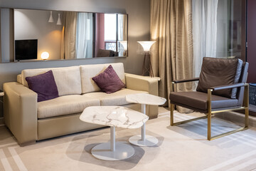 Interior of living room with sofa, armchair, tables and glowing lamps in evening. Stylish home...