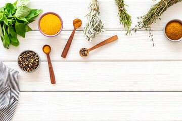 Frame of green herbs and spices in bowls for cooking, top view