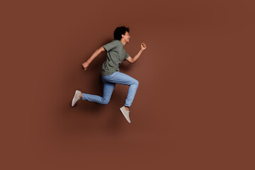 Full length photo of handsome young male running shopping sales dressed stylish khaki garment isolated on brown color background