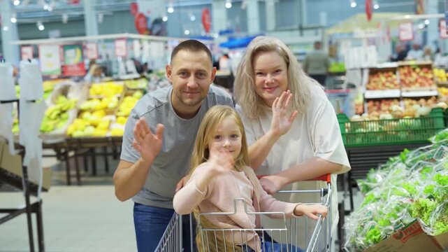 Portrait of happy family shopping in supermarket and looking at camera.