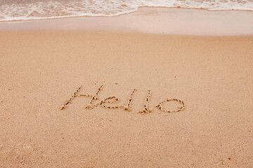 the inscription hello  on the seashore with palm trees