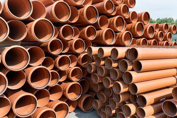 Fragment of a water supply system made  pipes, installation of automatic watering. Close-up PVC plumbing pipes stacked wooden pallets replacement at city street infrastructure construction site. Town 
