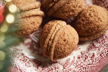 Close up of homemade Christmas cookies in the form of nuts filled with cream on a vintage plate
