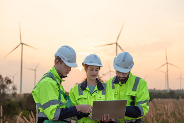 Team of engineers working and using a computer laptop on site in wind turbine farm, Wind turbines generate clean energy source, Eco technology for electric © surachetkhamsuk