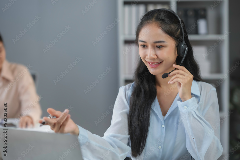 Poster smiling customer service agent is gesturing while talking through a headset in an office