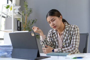 Asian businesswoman suffering from painful feeling in elbow during workday in office