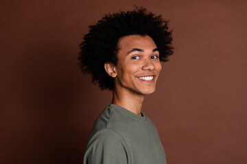 Portrait photo of young funky guy with curly haircut wearing gray casual t shirt toothy beaming smiling isolated on brown color background