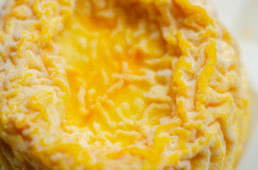 A yellow cheese is sitting in a paper wrapper