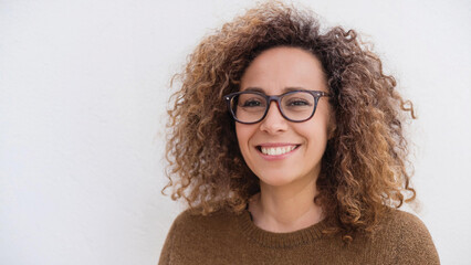 Smiling Woman with Dark Curly Hair and Glasses Wearing a Brown Sweater on a White Background
