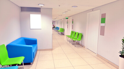 Modern waiting medical office area with white walls, a  tile floor and a row of armchairs.
