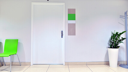 Modern waiting medical office area with white walls, a  tile floor and a row of armchairs.