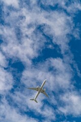 Naklejka premium White airplane flying high in the sky with scattered clouds and a blue background