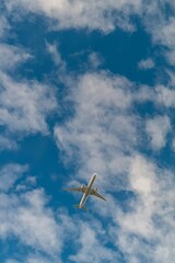 Commercial airplane flying high in the sky with scattered clouds