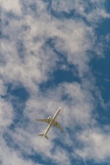 Commercial airplane flying high in the sky with scattered clouds