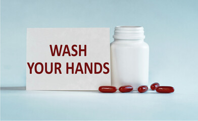 White Pill Bottle With Wash Your Hands Message and Red Pills on a Table