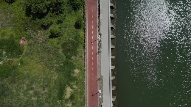 Bird's eye drone footage of a walkway and a bike path along the Nervion River in Leioa, Spain