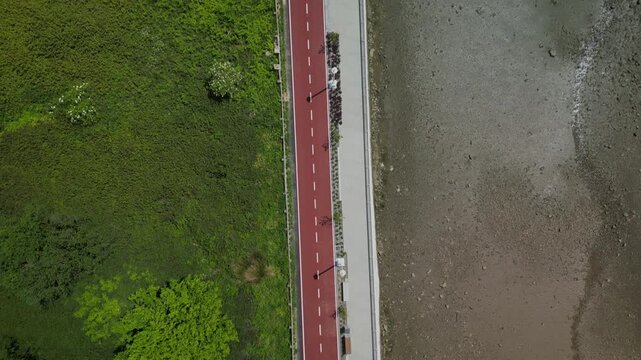 Bird's eye drone footage of a bike path and a walkway along the Nervion River in Leioa, Spain