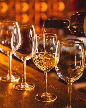 Bartender pouring white wine into glasses at bar counter