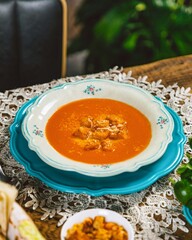 Tomato soup garnished with croutons and grated cheese being served on a table