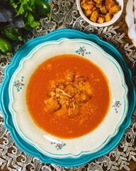 Tomato soup with croutons and grated cheese on a table