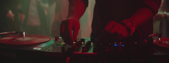 DJ's hands touching sliders, playing electronic music on the mixing deck, dance party in a nightclub. Slow-motion