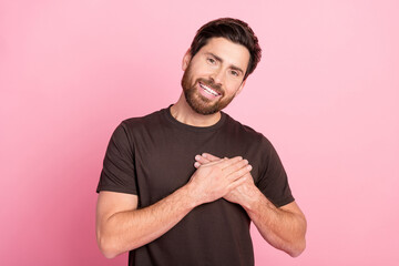 Photo of thankful grateful guy with stubble brunet hair dressed brown t-shirt hold arms on chest isolated on pink color background