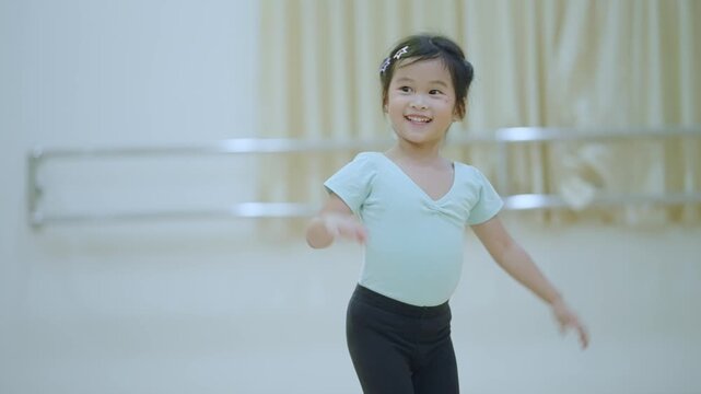 Asian little girl dancing inside indoor class, practicing jazz dance, child development activity performing lesson, children learning by playing, active happy kid, moving clapping hands, youth energy