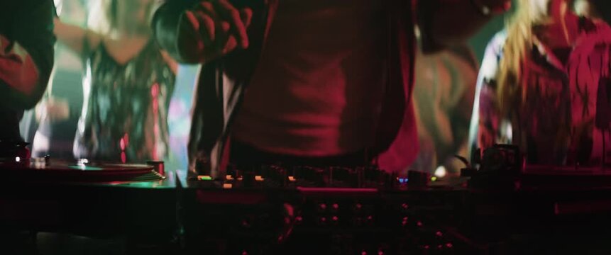 DJ mixing music with sound mixer panel and dancing in the middle of a crowd in night club