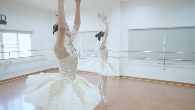Beautiful asian little girls in white tutu and pointe shoes dancing together with buddy in choreography class moving elegantly. Two Aesthetic ballet girls practice for upcoming competition. Skill Art