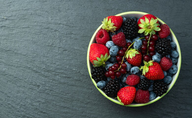 Mix of ripe colorful berries in bowl photography . Blueberry , strawberry , raspberry , blackberry and red currant . Top view