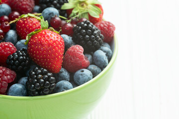 Mix of ripe colorful berries in bowl photography . Blueberry , strawberry , raspberry , blackberry and red currant . Top view