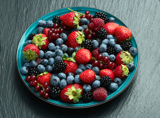 Mix of ripe colorful berries in bowl photography . Blueberry , strawberry , raspberry , blackberry and red currant . Top view