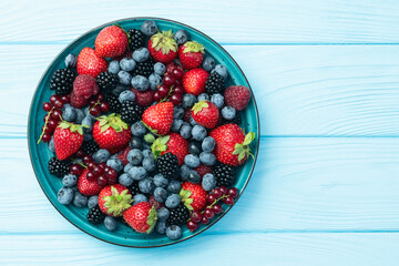 Mix of ripe colorful berries in bowl photography . Blueberry , strawberry , raspberry , blackberry and red currant . Top view