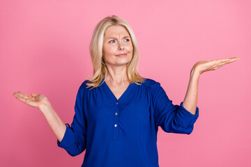 Obraz premium Photo portrait of lovely pensioner lady compare skeptical empty space dressed stylish blue garment isolated on pink color background