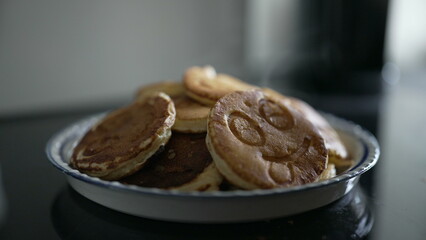 Close-up of a plate of smiley face pancakes stacked high. The detailed shot showcases a fun and delightful breakfast treat, emphasizing creativity and joy in food presentation