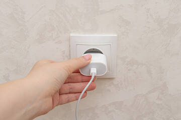 USB or type-c charging cable in electrical outlet. Woman puts a device on charge